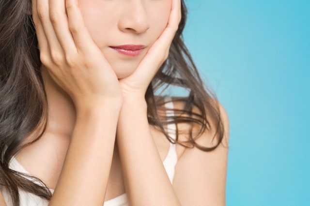 両手で顎を触れる女性